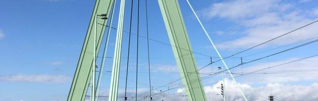 Schrägseilbrücke mit grünem Pylon vor blauem Himmel